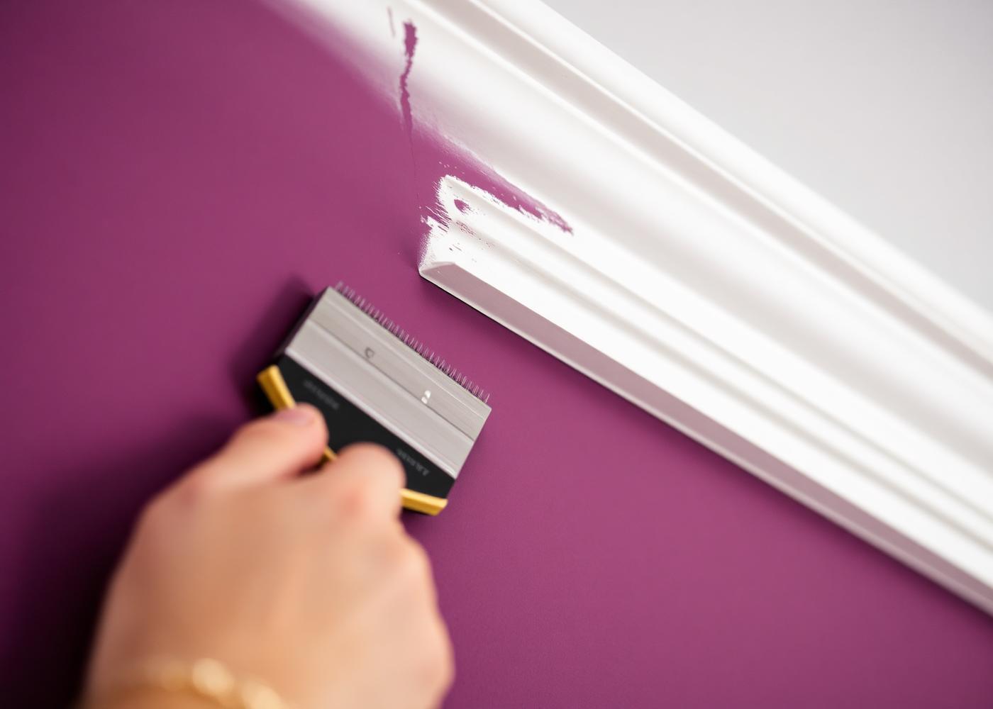 Brush cutting a crisp line between a plum wall and white cornice